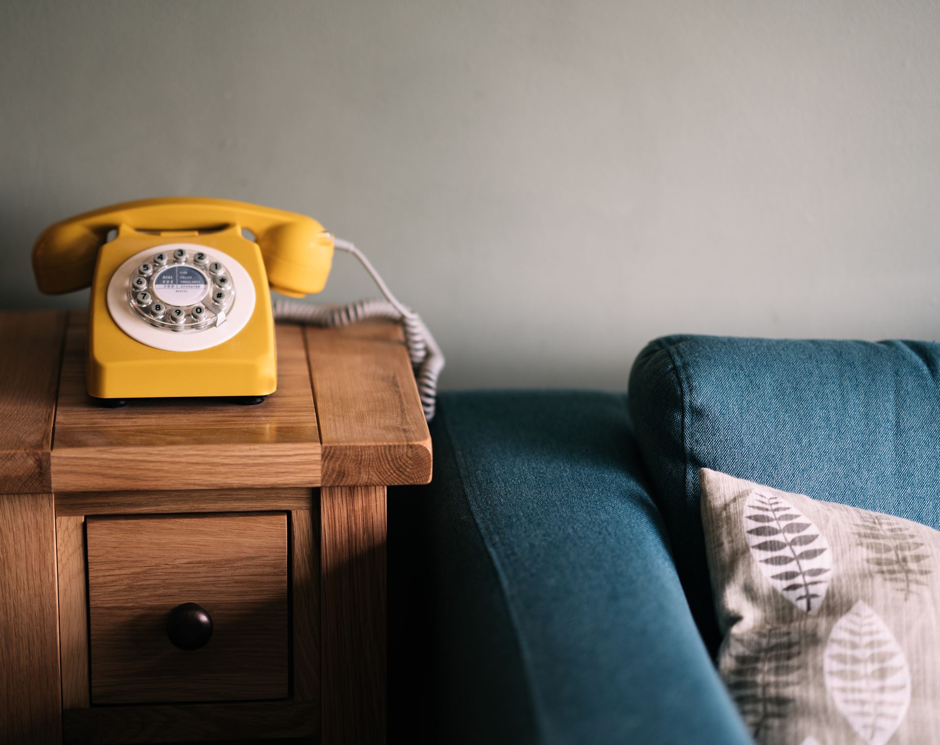 a yellow telephone sitting on top of a wooden table